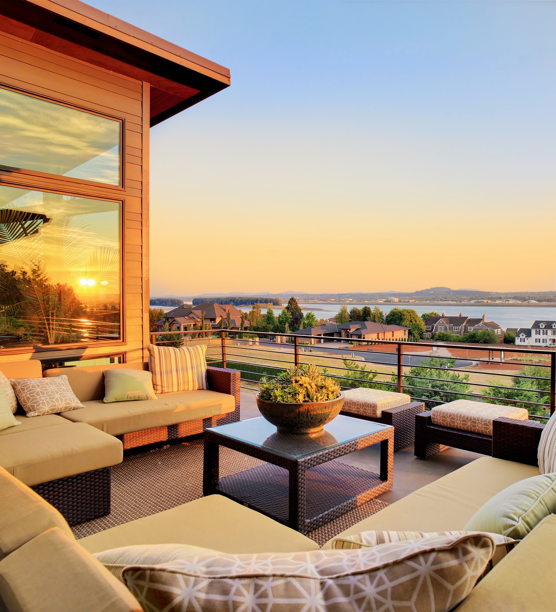 Cozy balcony view showcasing comfortable seating and a sunset over a lake, highlighting the tranquil atmosphere of outdoor living.